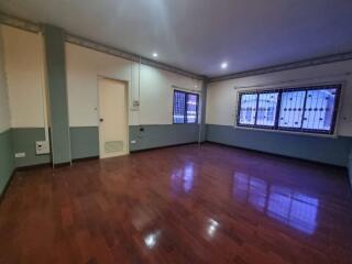 Spacious living room with wooden flooring and barred windows