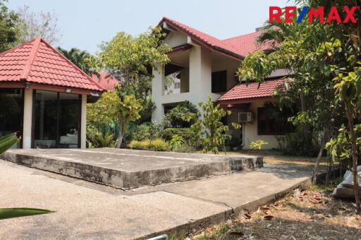 Exterior view of a residential house with a red-tiled roof and surrounding greenery