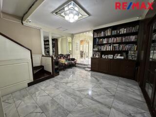Spacious living area with marble flooring, bookshelves, and stairway to the upper floor