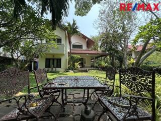 Outdoor seating area in a garden with a house in the background