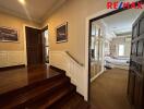 A view of the hallway featuring wooden flooring and a staircase leading up to a bedroom