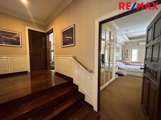 A view of the hallway featuring wooden flooring and a staircase leading up to a bedroom