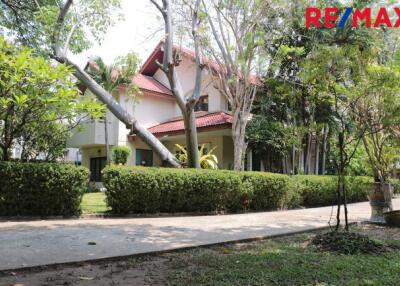 Two-story house with a red roof and lush garden