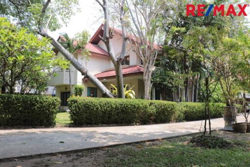 Two-story house with a red roof and lush garden