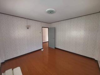 Empty bedroom with wooden floor and patterned wallpaper