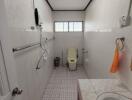 Bathroom with tiles, toilet, sink, shower, and a window.