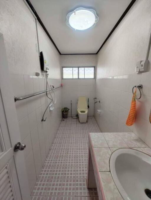 Bathroom with tiles, toilet, sink, shower, and a window.