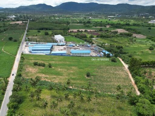 Aerial view of an industrial area surrounded by green fields and hills