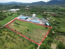 Aerial view of a large agricultural plot of land surrounded by greenery with industrial buildings nearby