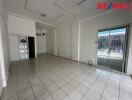 Empty interior space with tiled floor, sliding glass door and large window.