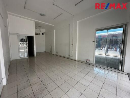 Empty interior space with tiled floor, sliding glass door and large window.