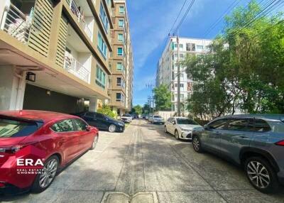 Parking area in front of buildings with various cars and trees