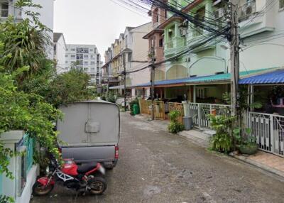 Street view of residential area with parked vehicles and townhouse buildings