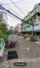 Street view of residential area with parked vehicles and townhouse buildings