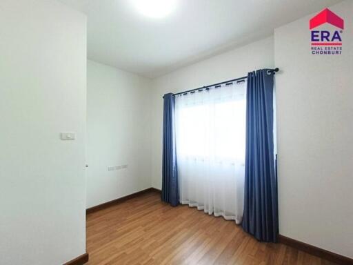 Minimalist bedroom with wooden floors, window, and blue curtains