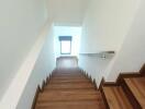 Wooden staircase with white walls and handrail