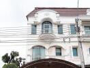 Front view of a multi-story residential building with balcony and arched windows