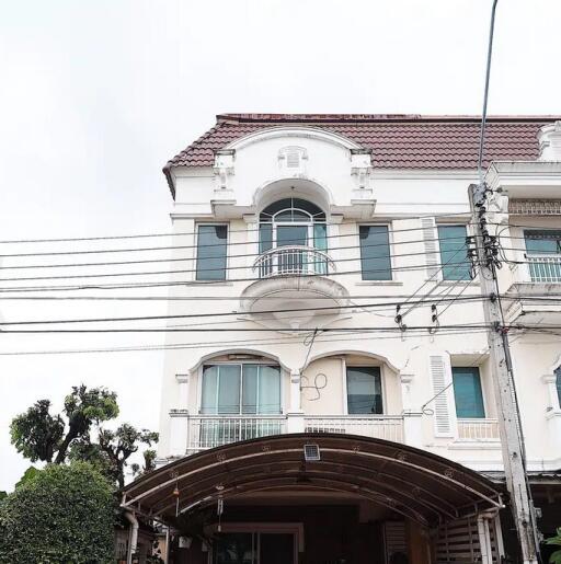 Front view of a multi-story residential building with balcony and arched windows