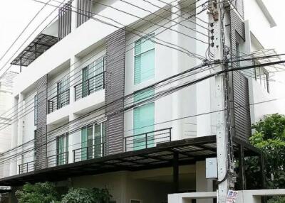 Modern multi-story building with balconies and lush greenery