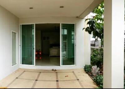 Covered patio area with sliding glass doors and greenery