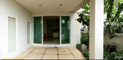 Covered patio area with sliding glass doors and greenery