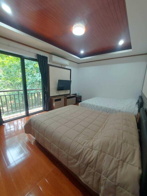 Spacious bedroom with two beds, a TV, and a balcony