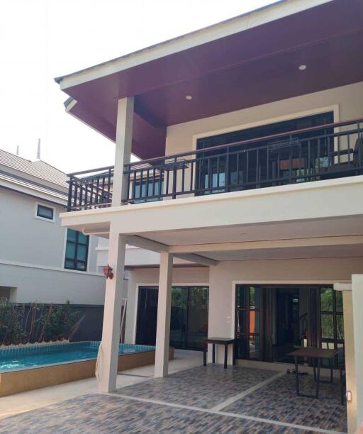 Exterior view of a modern two-story house with balcony and pool