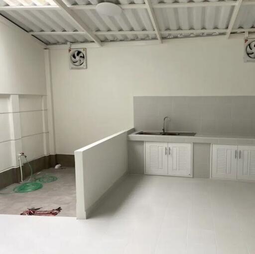 A clean, minimalist kitchen with white cabinets and a simple sink area.