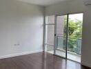 Spacious living room with hardwood floors and large windows leading to a balcony