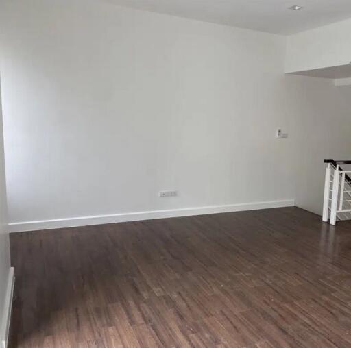 Spacious empty living room with wooden flooring and white walls