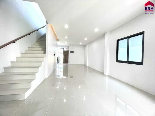 Bright, spacious living area with tiled flooring and staircase