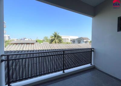 View from the balcony showing nearby roofs and a distant palm tree