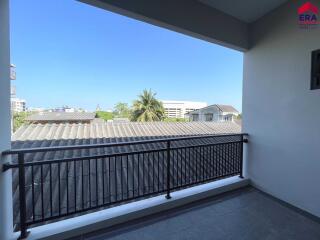 View from the balcony showing nearby roofs and a distant palm tree