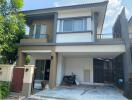 Modern two-storey house with a gated driveway and balcony