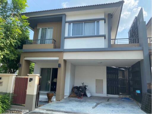 Modern two-storey house with a gated driveway and balcony