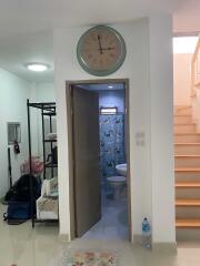 View of a hallway leading to a bathroom with a clock above the door