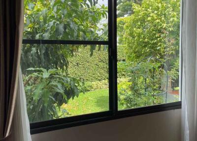 Bright bedroom with a large window overlooking a lush garden