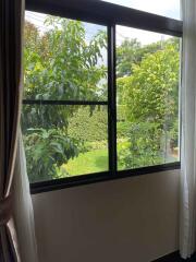 Bright bedroom with a large window overlooking a lush garden