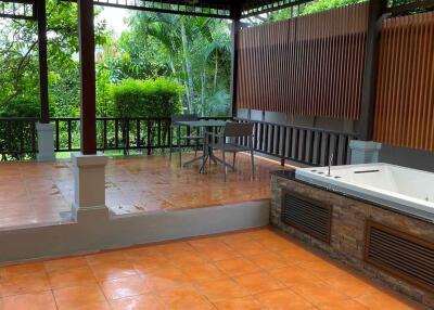 Spacious outdoor patio with tiled flooring and a covered sitting area.