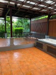 Spacious outdoor patio with tiled flooring and a covered sitting area.
