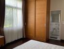 Bedroom with large window, wooden wardrobe, and ensuite bathroom