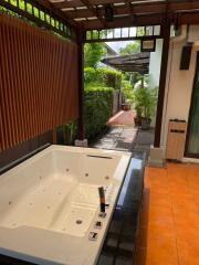 Outdoor area with jacuzzi and covered patio