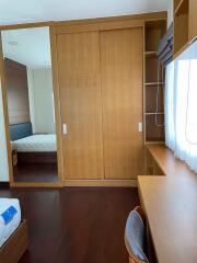 Bedroom with wooden furniture, a bed, wardrobe with mirror, desk, and window with white curtains