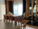 Modern dining area with wooden table and chairs, featuring large windows with curtains and built-in shelving.