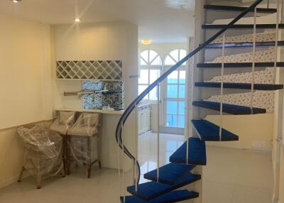 Spiral staircase in a bright living area with kitchen in the background