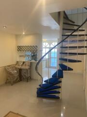 Spiral staircase in a bright living area with kitchen in the background