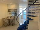 Spiral staircase in a bright living area with kitchen in the background