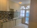 Bright kitchen with tiled backsplash and arched windowed door