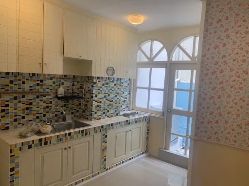 Bright kitchen with tiled backsplash and arched windowed door