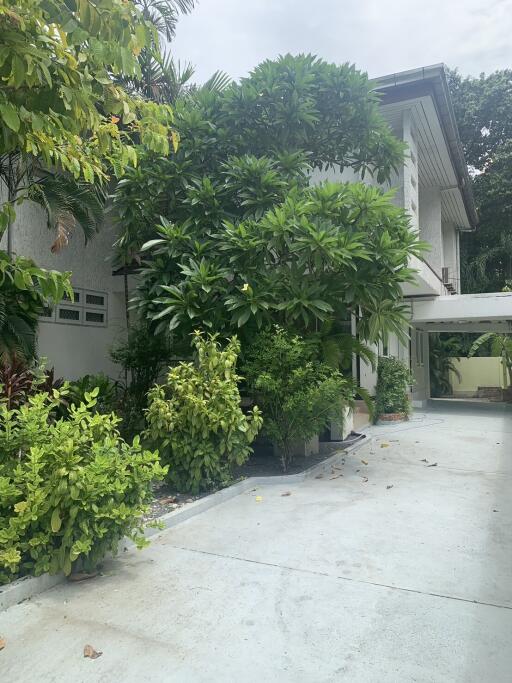 Well-maintained exterior with lush greenery and driveway